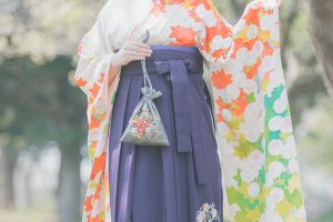 紫の袴にオレンジと緑の振袖を着た女性