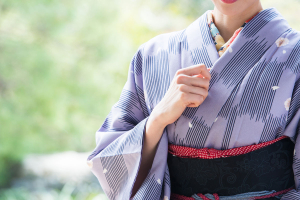 紫の着物に赤い半幅帯と紫の袴を着た女性