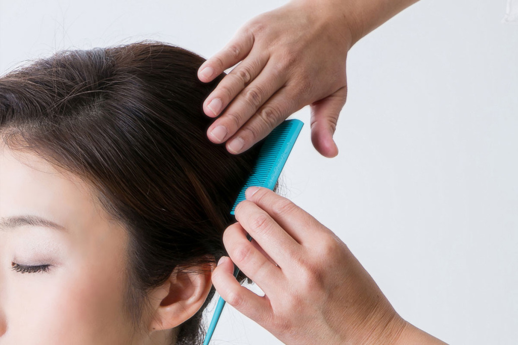 前髪のスタイリングをする黒留袖をきた女性