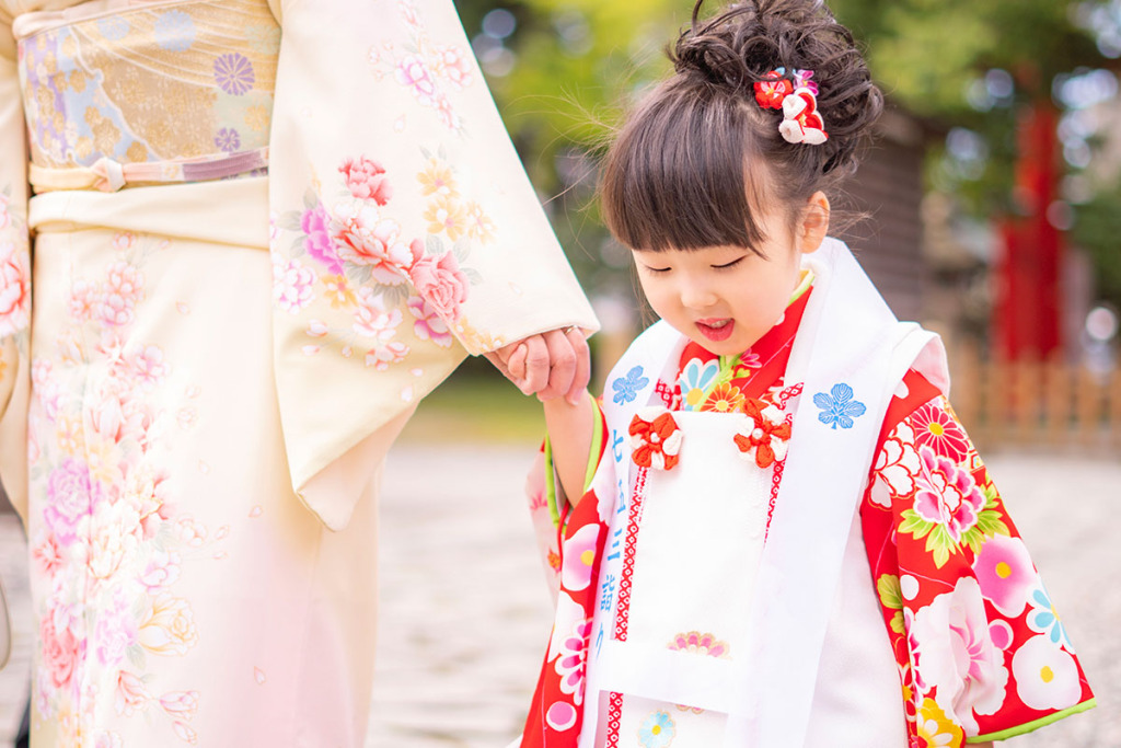 白い被布に赤い着物を着た女の子とクリーム色の訪問着を着た女性