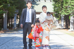 スーツを着た男性とベージュの着物を着た女性と赤い被布着物を着た女の子と赤ちゃん