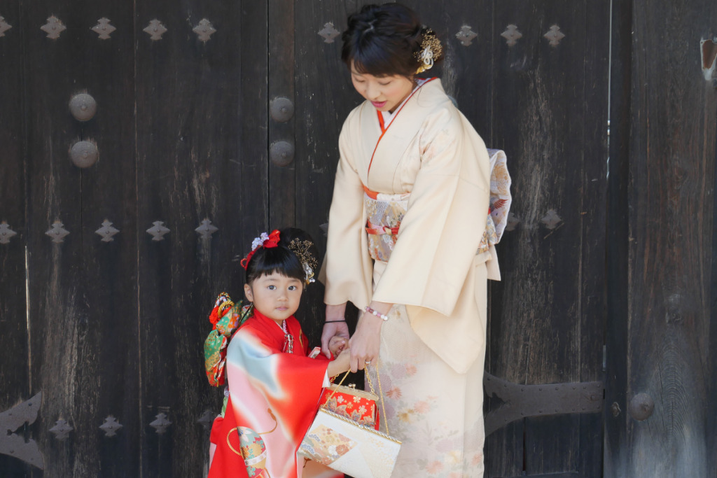 ベージュの訪問着を着た女性と赤い着物を着た女の子