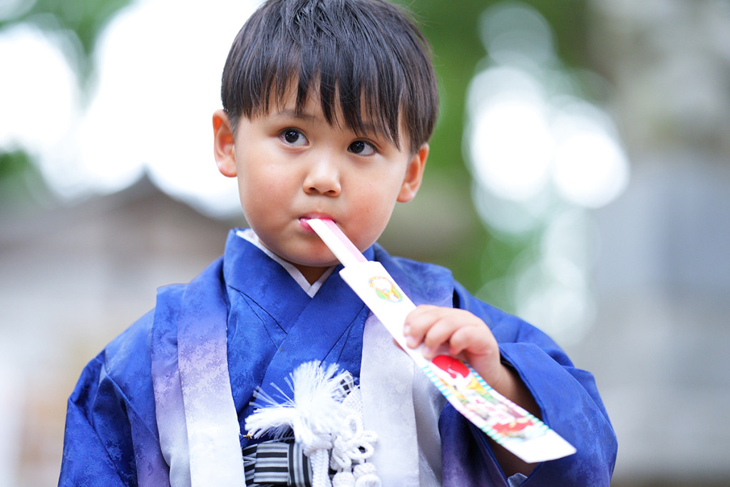 七五三の千歳飴を食べる羽織袴を着た男の子