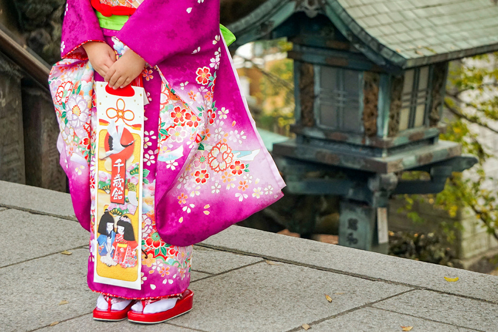 千歳飴をもった紫色の着物を着た女の子