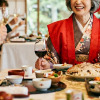 赤いちゃんちゃんこを着て食事をする女性